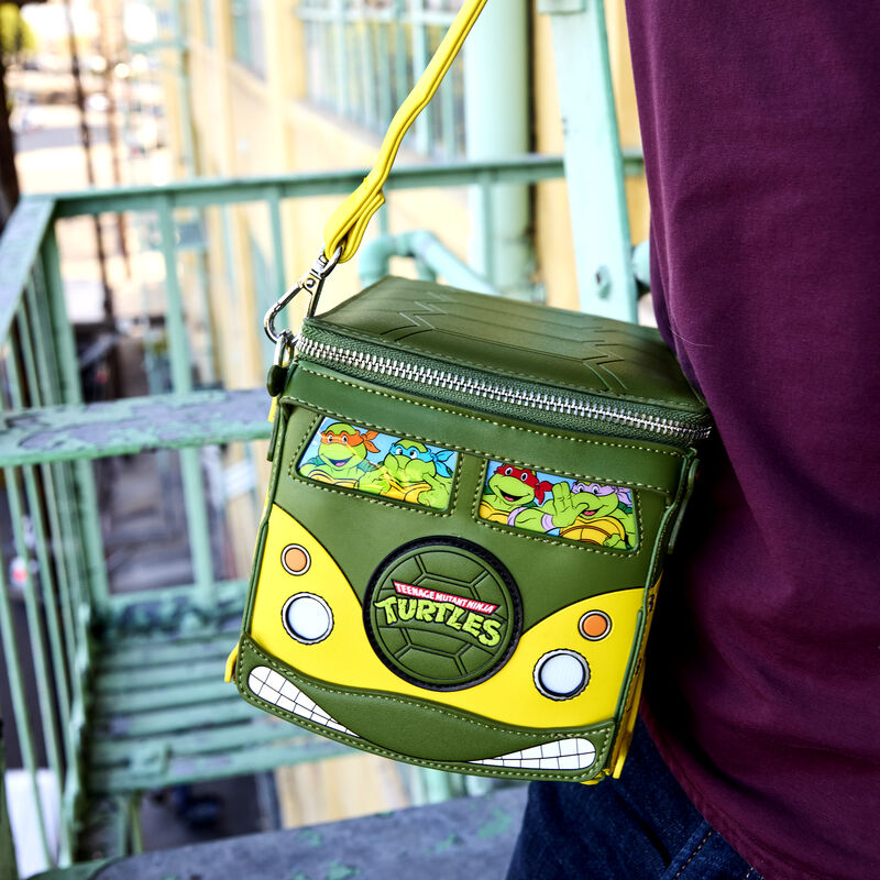 Close up shot of the Loungefly Teenage Mutant Ninja Turtles figural crossbody bag that looks like the party wagon, showing off the front, where the turtles are looking out from the front windows. The center of the front of the bus has the TMNT logo. 